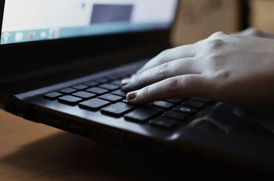 Hände tippen auf einer dunklen Laptop-Tastatur