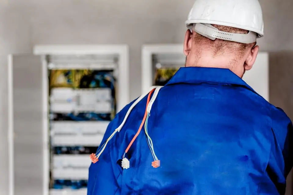 Elektriker mit Schutzhelm arbeitet an einem Schaltschrank