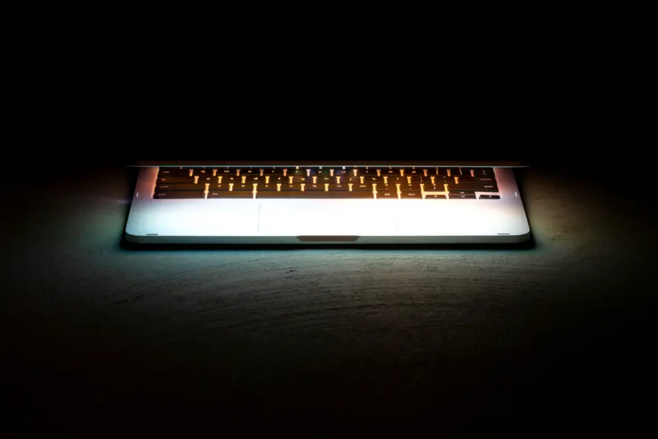 Aufgeklappter Laptop mit beleuchteter Tastatur in einem dunklen Raum